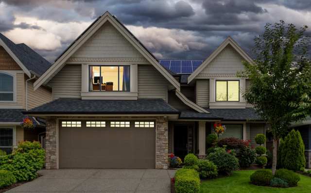 Image of home front with lights on and stormy sky